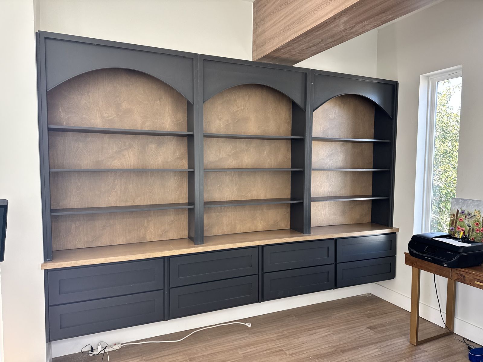 Navy built-in wall unit with three arched wood-backed bookshelves over drawers