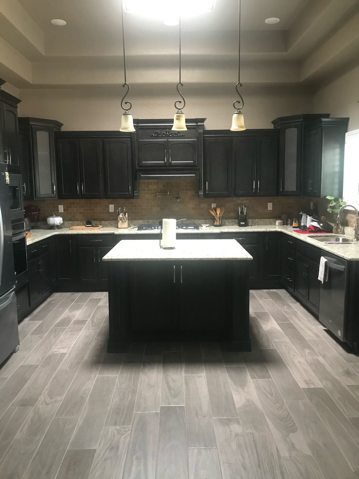 Espresso kitchen with granite counters, center island and three pendant lights