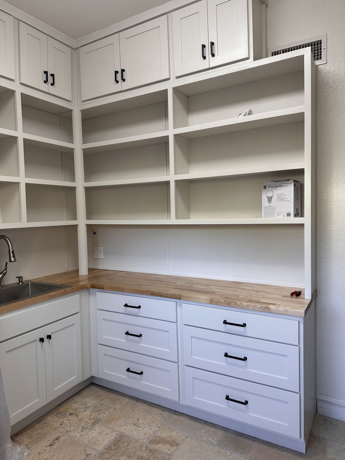 White butler's pantry with open shelves, shaker drawers and a butcher-block countertop