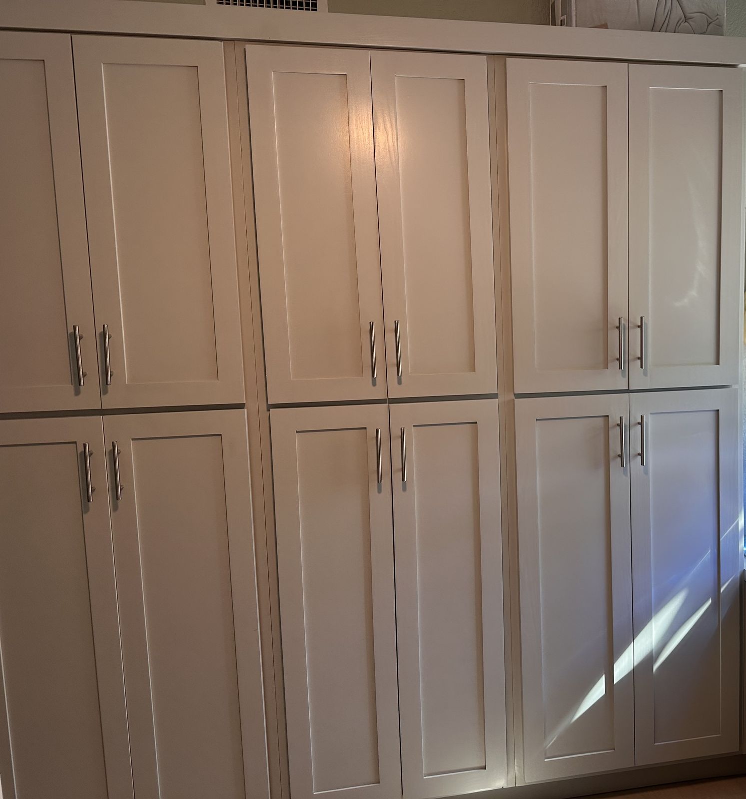 Wall of tall white shaker pantry cabinets